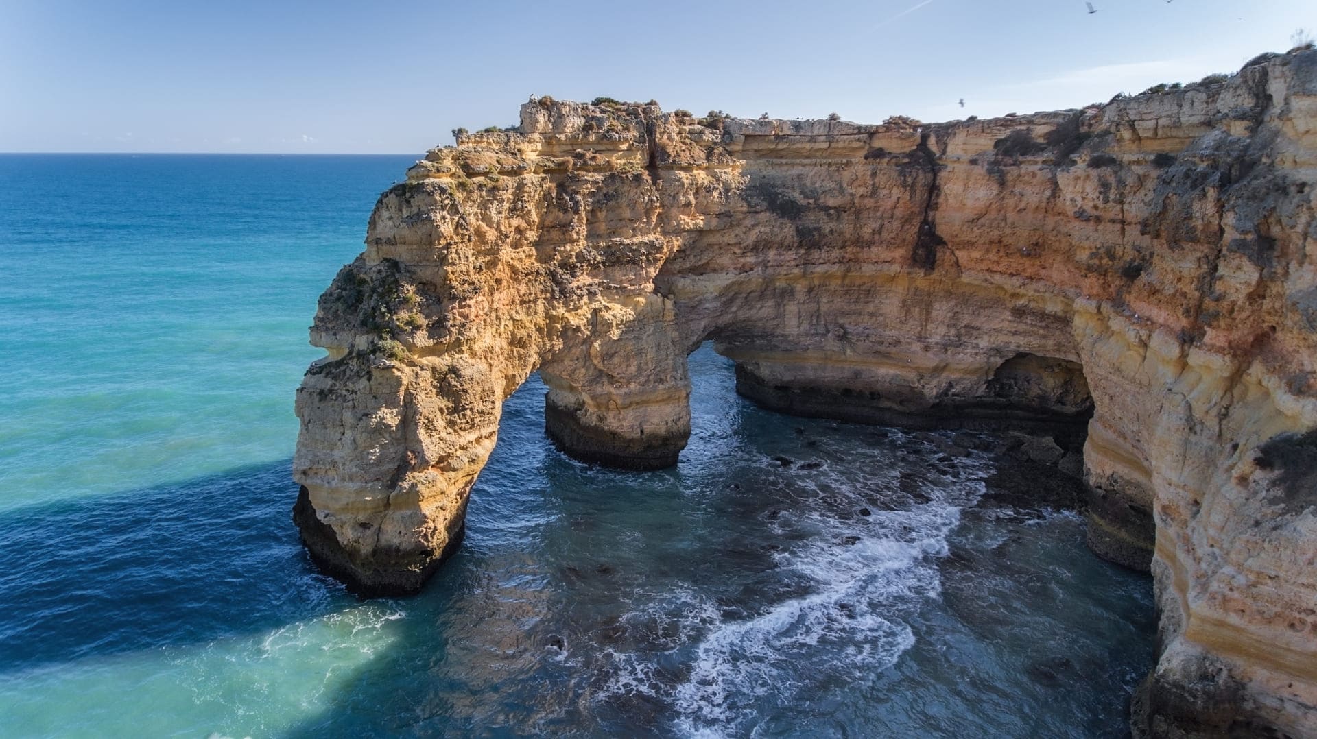 Praia da Marinha com falésias e mar azul.